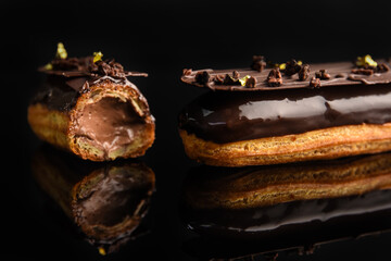 Eclair stuffed in chocolate on a black background..