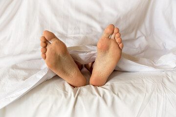 Obraz na płótnie Canvas Men feet alone in a bed