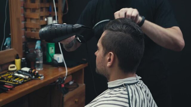 Barber drying hair of man in barbershop