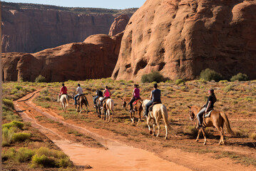 People horse back riding through Monument Valley in Utah