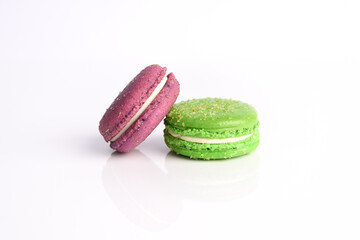 Two purple and green macarons cookies on a white background..