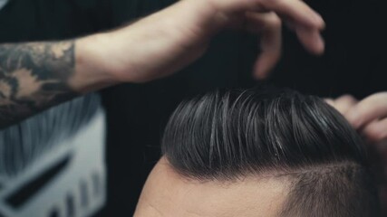 Cropped view of barber styling hair of client after haircut
