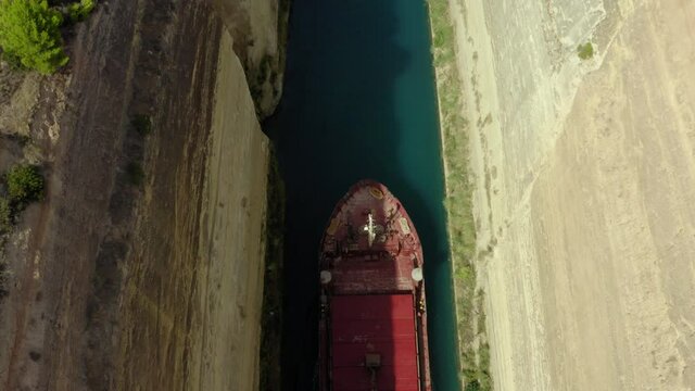 Aerial Shot Of Barge Amidst Rocky Cliffs At Corinth Canal, Drone Flying Backward Over Boat