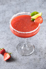 Strawberry Margarita cocktail or smoothie garnish lime on gray background. Vertical orientation. Freshness summer alcoholic beverage. Close up. Alcoholic Margarita cocktail made of strawberry puree