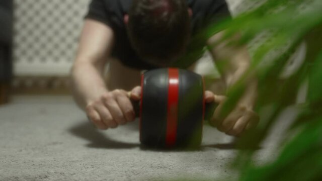 Man doing exercise with abs roller wheel at home.