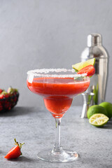 Strawberry Margarita cocktail or smoothie garnish lime on gray background. Freshness summer alcoholic beverage. Vertical format. Alcoholic Margarita cocktail made of strawberry puree, lime juice and