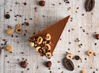 Chocolate cheesecake with hazelnuts on a white wooden background. A slice of cake with coffee..