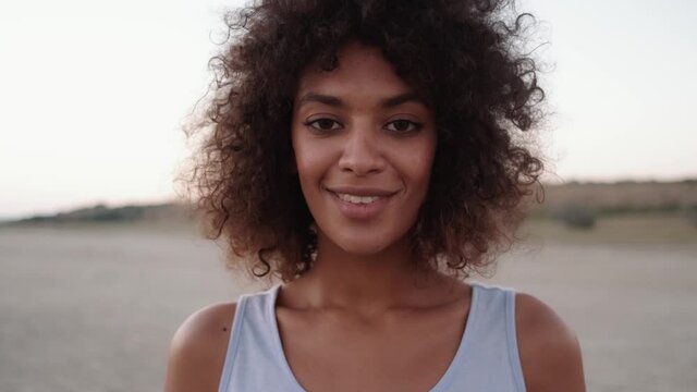 The close-up view of the African smiling woman opening her eyes to a camera in the nature