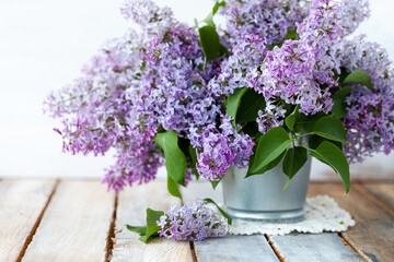 Beautiful fresh violet lilac bouquet in metal can. Greeting card for Birthday, Mother's day, Saint Valentine's Day, 8 march, Women's day. White wooden background, close up with copy space for text