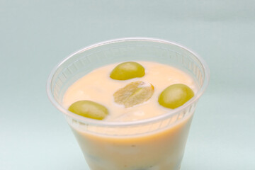 sweet condensed milk with grape in a glass with blue background.