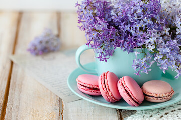 Postcard with violet lilac bouquet in a blue cup and delicious french macarons. Template for birthday card, greeting for Mother's Day, Saint Valentine's day, 8 March, Women's Day. White background