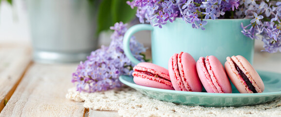 Postcard with violet lilac bouquet in a blue cup and delicious french macarons. Template for birthday card, greeting for Mother's Day, Saint Valentine's day, Women's Day. White background banner