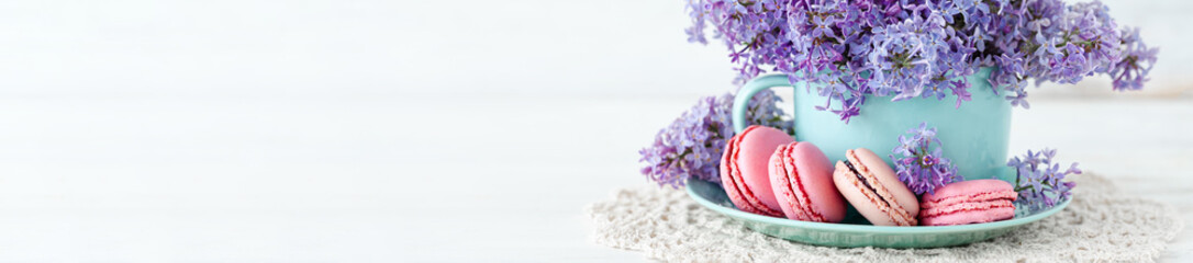 Violet lilac bouquet in a blue cup and delicious french macarons. Template for birthday card, greeting for Mother's Day, Saint Valentine's day, 8 March, Women's Day. White background banner
