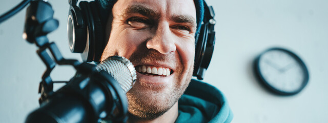 Handsome content creator streaming his live podcast using professional microphone at his broadcast...