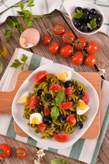 Fusilli pasta with cherry tomatoes, eggs and black olives.