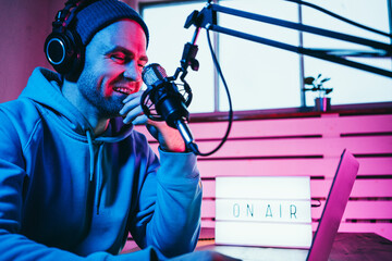 Streamer  broadcasting his live audio show at home studio using stylish cyber punk blue magenta...