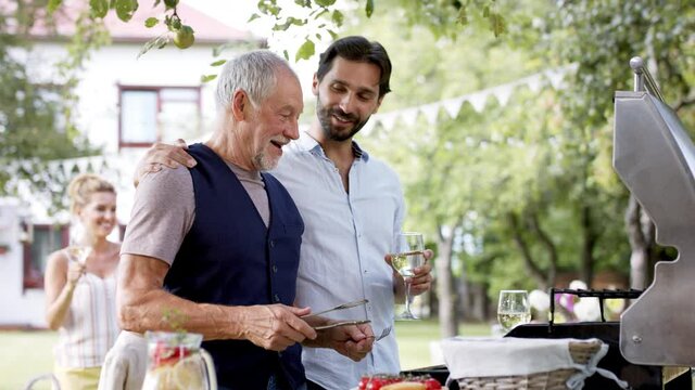 Family having a garden party, father with son barbecuing.