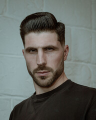 portrait of a man with stylish haircut on the white wall background