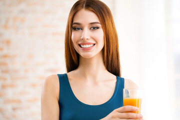Portrait of happy smiling young beautiful woman drinking orange juice. Beautiful girl in casual blue dress - healthy eating, beauty and dieting concept. Weight loss.