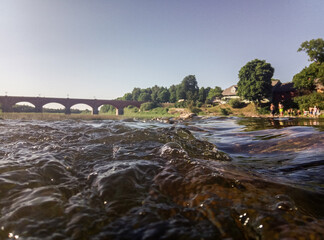 Long brick bridge and Venta river, photographed from a very low level, Kuldiga, Latvia.