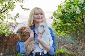 Beautiful smiling girl teenager with a couple of decorative rabbits