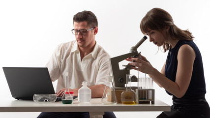 Man and a woman are conducting laboratory research. Man and woman laboratory researcher. laboratory researchers on a white background. They use a laptop and a microscope. Scientific research.