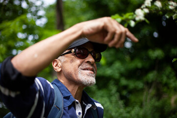 Latino American man in sunglasses likes a flowering branch in spring