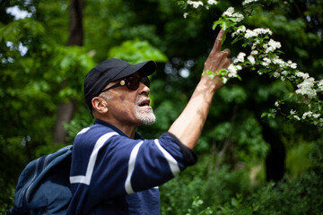 Latino American man in sunglasses likes a flowering branch in spring