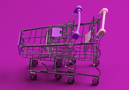 Two mini supermarket trolleys on blue background. Shopping concept.