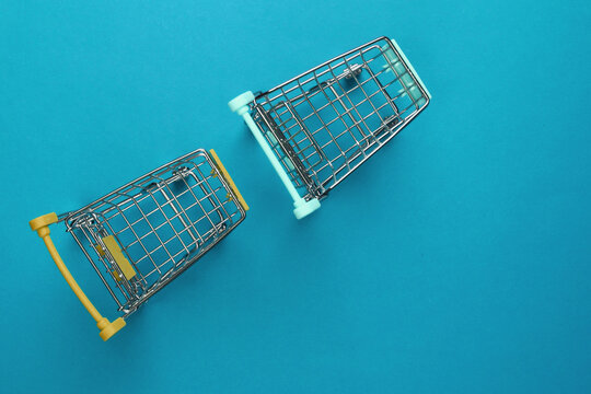 Two mini supermarket trolleys on blue background. Shopping concept. Top view. Minimalism