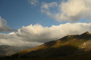 Clouds hanging over the rugged mountains of Du Toitskloof with a bright sun shining on it