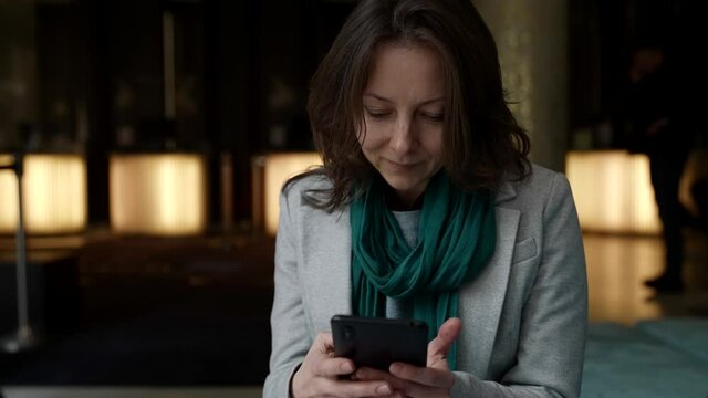 middle aged woman with modern smartphone in public place, medium portrait of lady with gadget