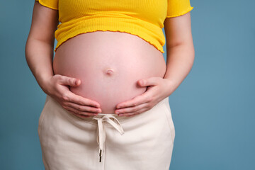 A pregnant woman in white pants and a yellow jacket