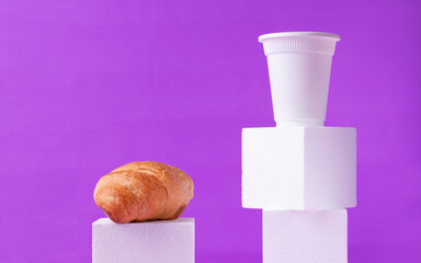Croissant and disposable cup of hot drink on white podium against the purple background. Takeaway food and drink