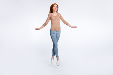 Full length photo of adorable charming ginger lady wear beige shirt smiling jumping high isolated white color background
