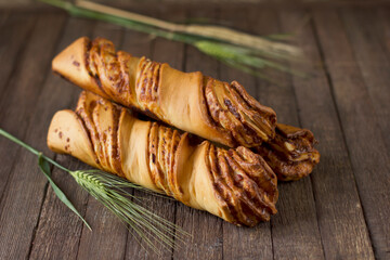 Bread art. Сraft rolled bread.  Cheese and bacon buns on an old wooden background with green wheat ears