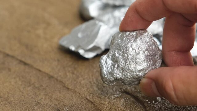 Miners hold platinum or silver in their hands found in mines for consideration.
