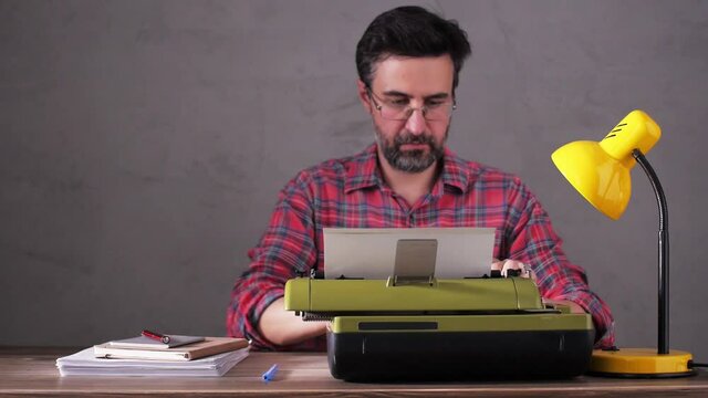 Man typing on a typewriter sitting at table thinking idea. Writer or screenwriter with typewriter. Creative inspiration concep