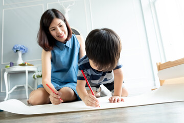Little toddler boy 3 years old drawing with his mom on the ground. Preschool learning activity. Happy family time concept. Selective Focus.