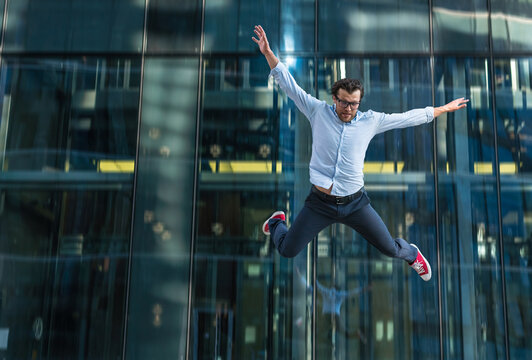 Man in casual wear falling off modern glass building