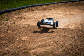 White Radio Controlled (RC) Offroad Truggy on an outdoor track training during sunny day
