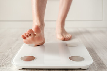 Woman foot takes a step onto a smart scale that makes bioelectric impedance analysis, BIA, body fat...