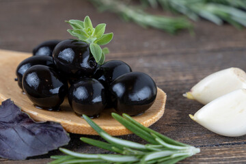 olives with spices and rosemary in a wooden spoon