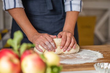 Female hands making dough. Dough with flour, eggs and other utensil, ingredients lies on white wooden table. Baking homemade process.