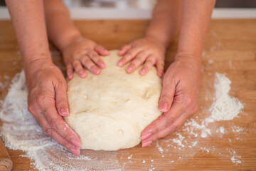Grandmother and granddaughter using cookie cutter to cut dough in shapes. Little cute girl and...