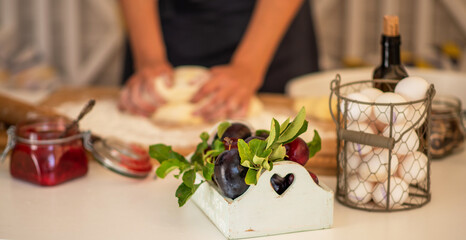 Female hands making dough. Dough with flour, eggs and other utensil, ingredients lies on white wooden table. Baking homemade process.