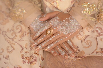 Asian bride's hands with henna patterns and art on white henna color