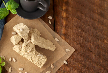 Eastern sweets. Sunflower halva on parchment paper on a wooden background with a blue napkin. Natural vegan product. Rustic style. Top view. Flat lay. Copy space.