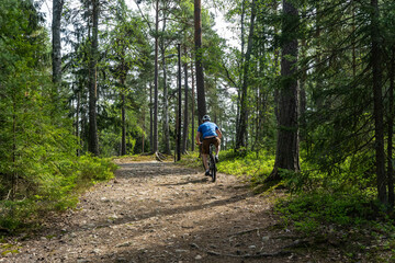 Obraz premium Man Cyclist on sport mountain bike on forest track. Male mountain bike racer cycling on trail with tree roots. Mountain biker rides in spring fresh air forest. Sports motivation and inspiration.
