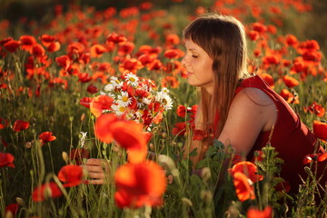 Girl in a field with a bouquet of daisies and poppies
